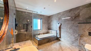Un baño moderno con ducha envuelta en vidrio, bañera y un espejo grande.