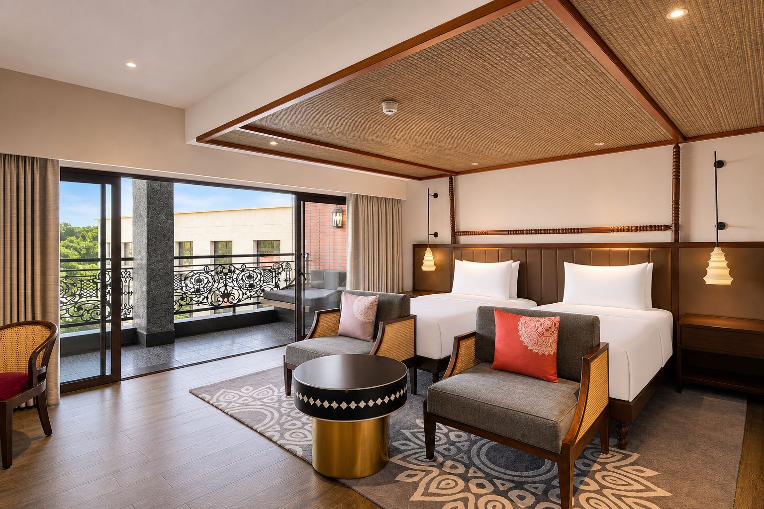 Habitación de hotel con balcón, cama, dos sillones, una mesa redonda y una alfombra estampada.