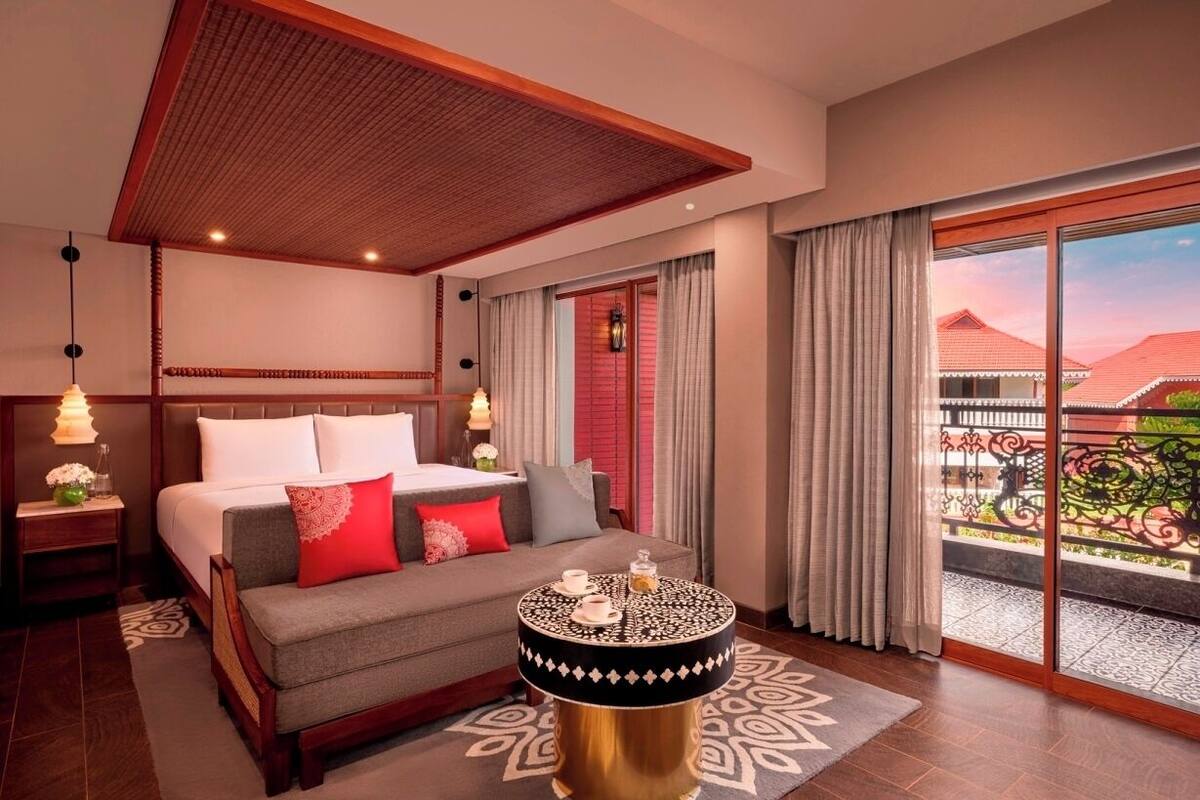 Ein Hotelzimmer mit Bett, rundem Tisch, Nachttisch und Blick ins Freie.