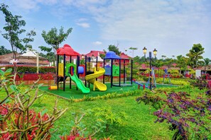 A playground with slides and climbing structures, surrounded by well-maintained grass and trees. - Gateway Bekal (Hosdurg)