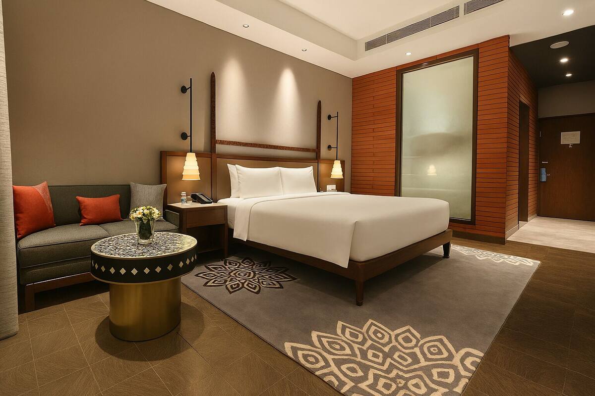 Ein Hotelzimmer mit Bett, Sofa, Nachttisch, Lampe und einem dekorativen Teppich.
