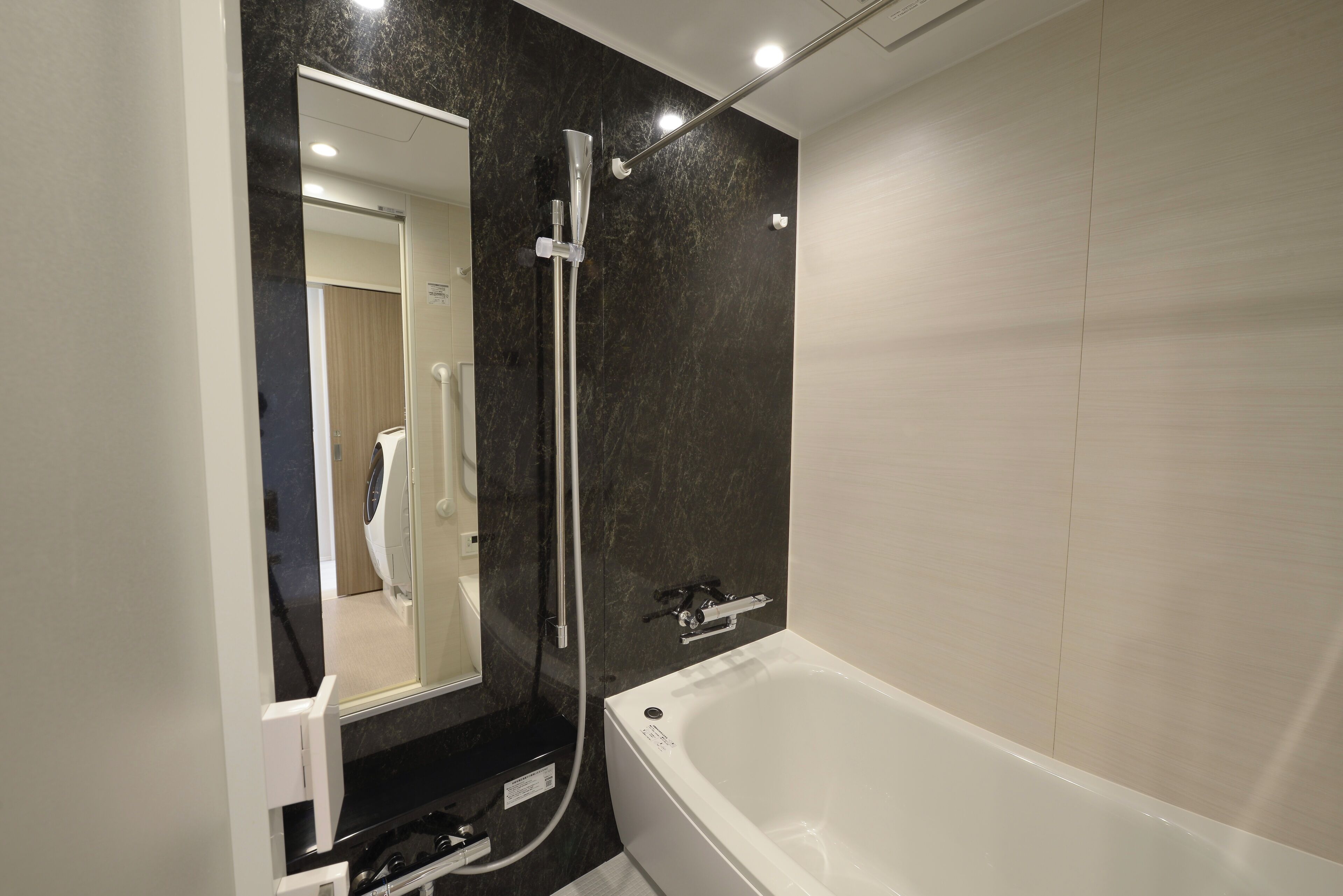 A modern bathroom with a bathtub, a shower with a glass enclosure, and a large mirror.