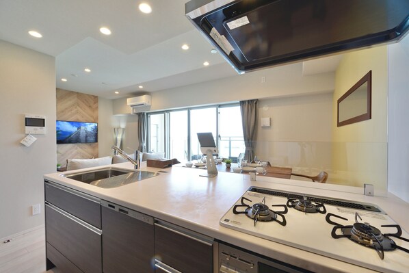 A modern kitchen with a central island, stainless steel appliances, and a large window providing natural light. - Branchera naha akebono premist R65 (Naha)