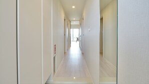 A narrow, well-lit hallway with a light wooden floor and white walls. - Branchera naha akebono premist R65 (Naha)