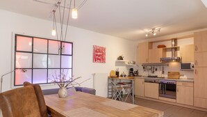 Une cuisine moderne avec des meubles en bois, une table à manger avec des chaises, une grande fenêtre offrant une belle vue et un luminaire suspendu.