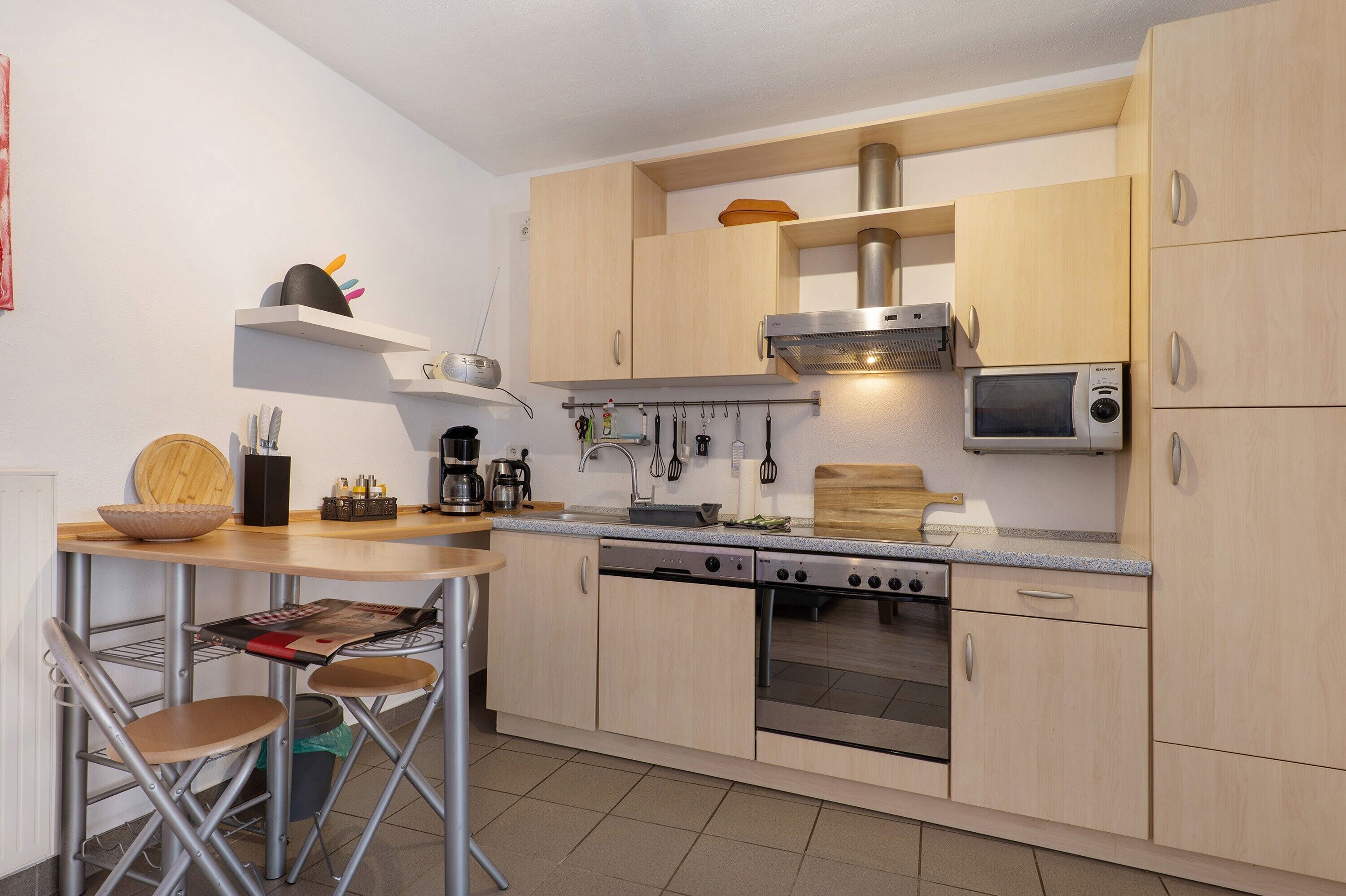 Eine kompakte Küche mit Herd, Backofen, Mikrowelle und Holzschränken.