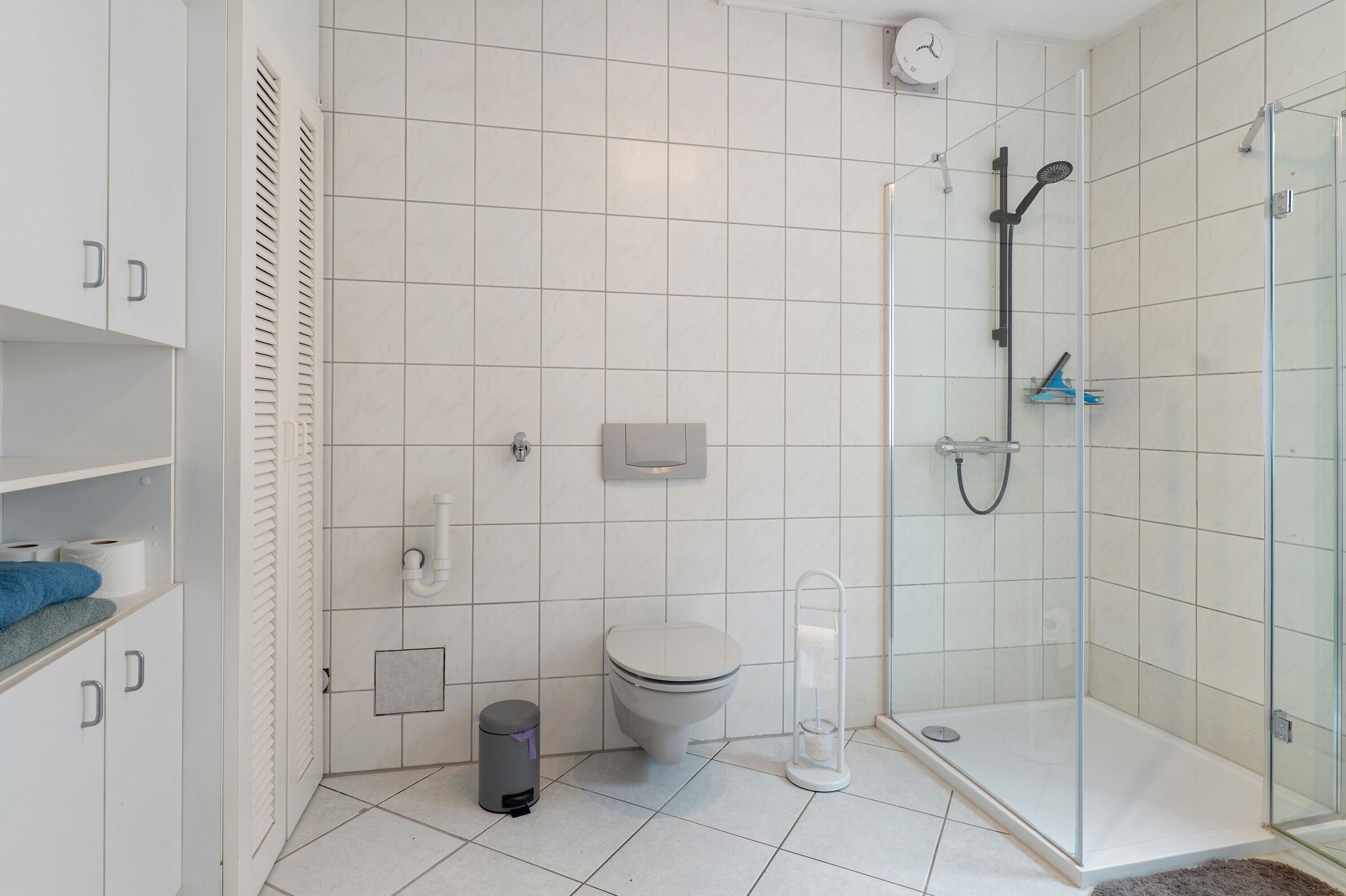 A modern bathroom with a toilet, shower, and storage cabinets.