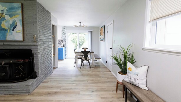 A modern living room with a fireplace, a dining area, and a bench with a decorative pillow. - Centrally located, newly renovated home (Federal Way)