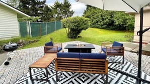 An outdoor patio with a table and chairs, a grill, and a patterned rug. - Centrally located, newly renovated home (Federal Way)