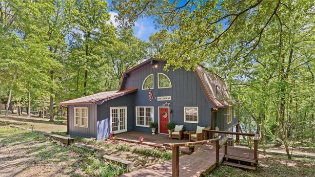 A rustic cabin with a porch, a red door, and a small deck. - Private Lake House near Enterprise (New Brockton)