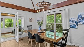 A dining area with a wooden table, black chairs, and a unique ceiling light fixture. - Private Lake House near Enterprise (New Brockton)