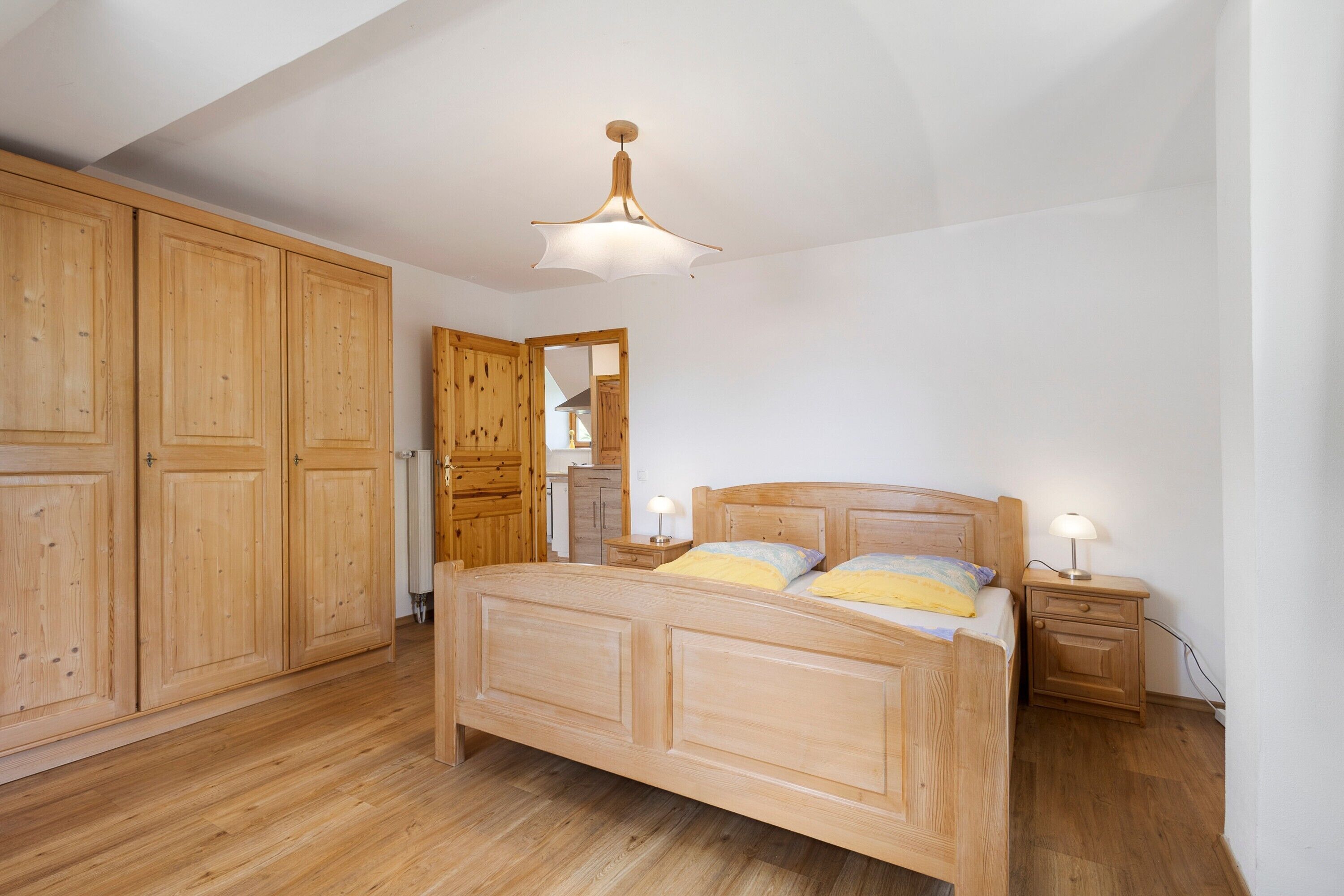 A bedroom with a wooden bed, nightstands, and a wardrobe.