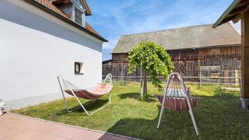 Un jardin avec un hamac, une balançoire et un petit arbre.