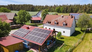Ein Landhaus mit rotem Dach, Solaranlage und umzäunter Garten.