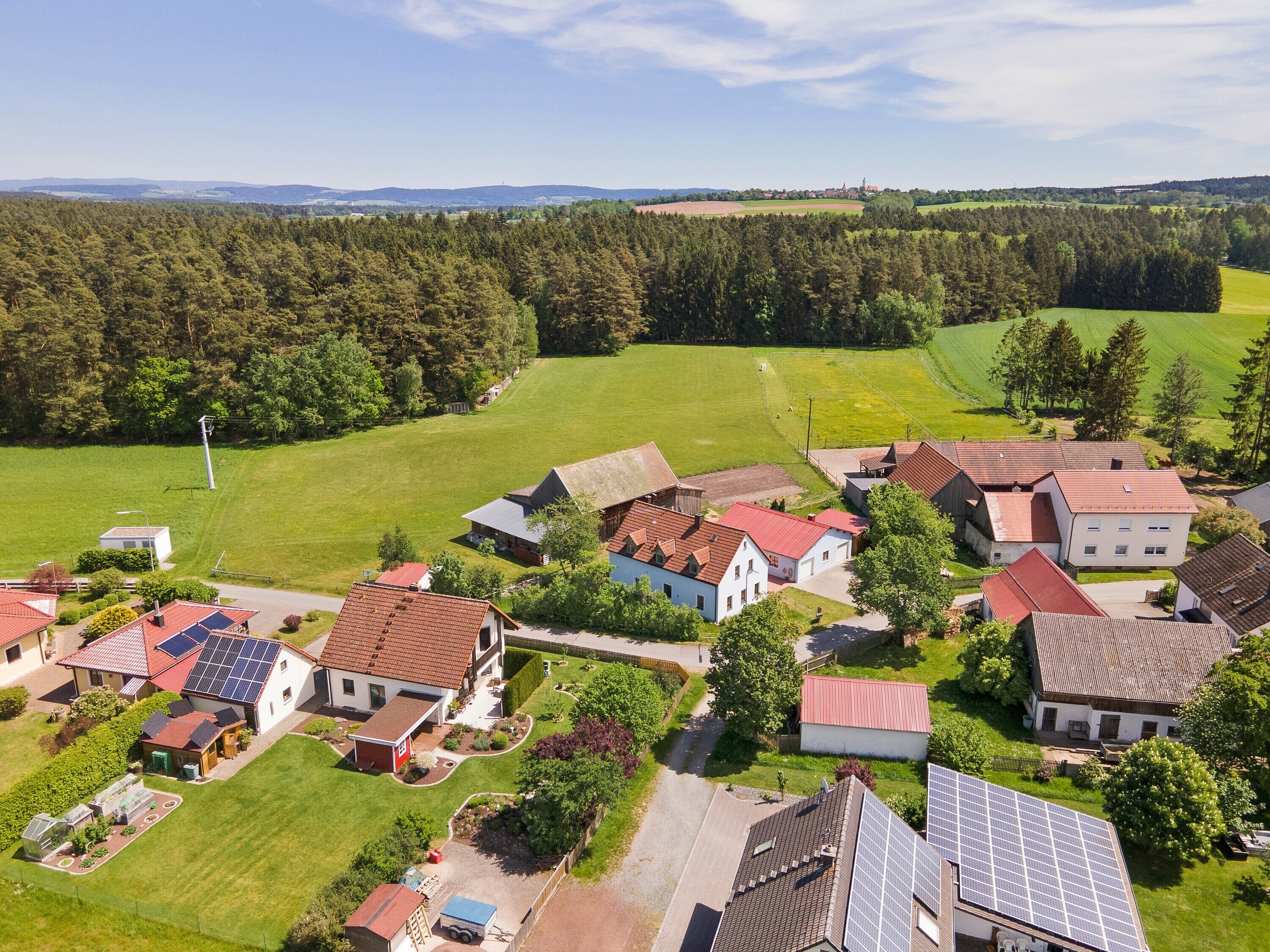 A residential area with houses, solar panels, and a green field.