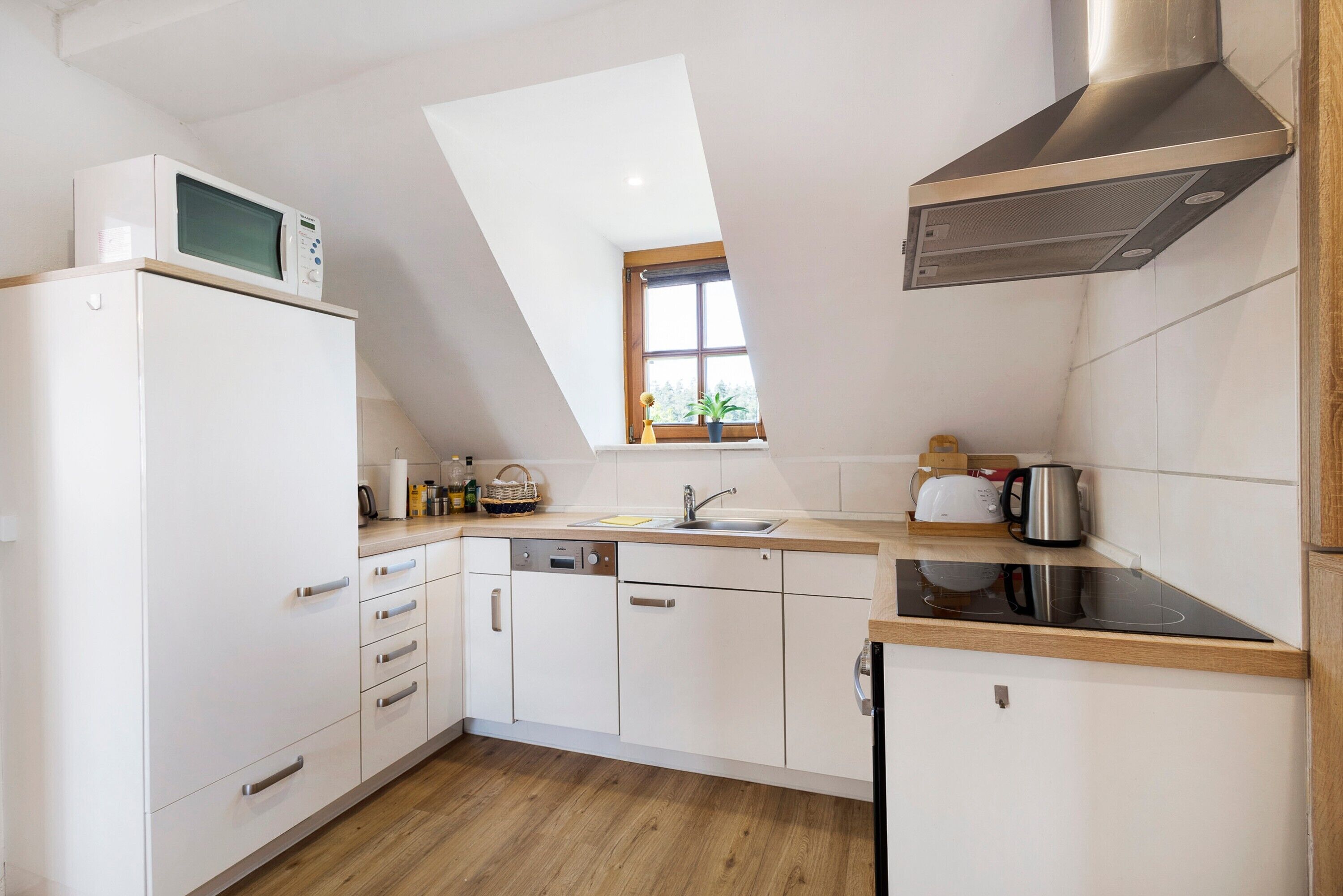 A modern kitchen with white cabinetry, a microwave, a sink, and a stove.