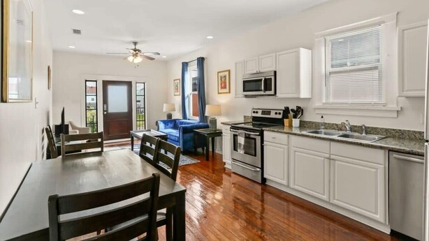 A modern kitchen with white cabinets, stainless steel appliances, and a granite countertop.