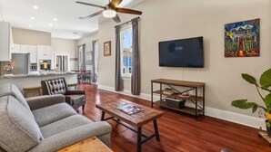 A modern living room with a grey sofa, wooden coffee table, and a TV on the wall.