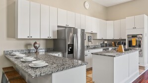 A modern kitchen with white cabinets, granite countertops, stainless steel appliances, and a central island with seating.