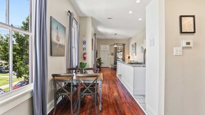 A spacious kitchen with a wooden floor, a dining area with a table and chairs, and a view of the outdoors through large windows.