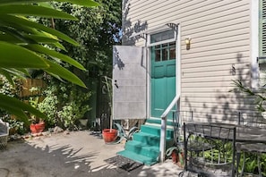 A house with a green door, a metal staircase, and a metal table and chair set outside.