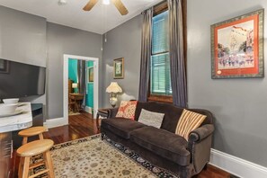 A living room with a dark brown sofa, a wooden coffee table, a patterned rug, and a television on a stand.
