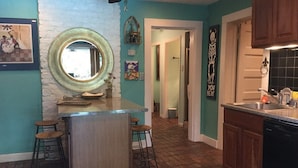 Una cocina con una isla central, taburetes de bar, un espejo y un adorno en la pared.
