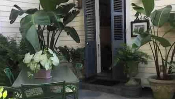 Un patio con una mesa y sillas, rodeado de plantas en macetas.