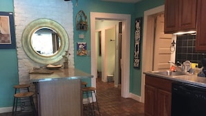 Una cocina con una isla central, taburetes, un espejo grande y un tapete estampado.