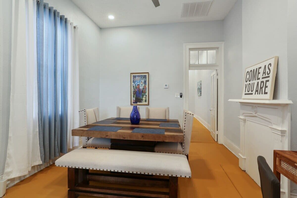 A dining area with a wooden table, cushioned benches, and a blue vase.
