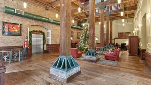 Een ruime lobby met houten balken, een kerstboom en een open haard.