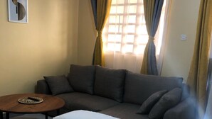 A living room with a sectional sofa, a round coffee table, and a white throw blanket.