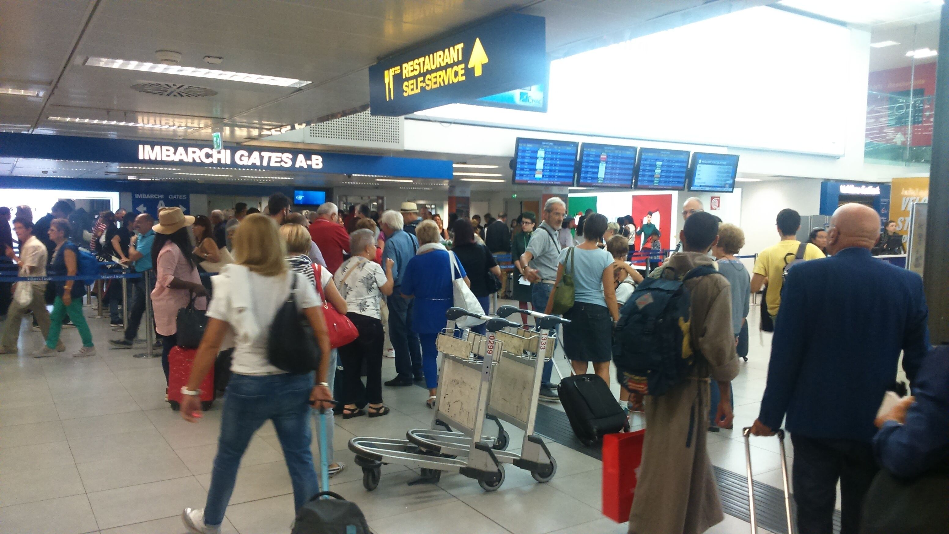 Un terminal d’aéroport très fréquenté, avec un panneau indiquant le premier restaurant en libre-service.