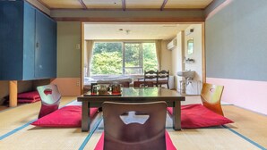 A traditional Japanese-style room with tatami flooring, a low table, and a view of a lush garden through large windows. - Tabist Shiobaraonsen Kashiwaya Ryokan (Nasushiobara)