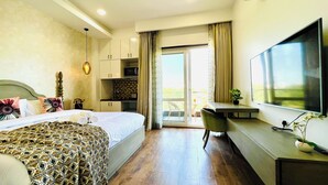 Ein Hotelzimmer mit Bett, Schreibtisch, Fernseher und Balkon.