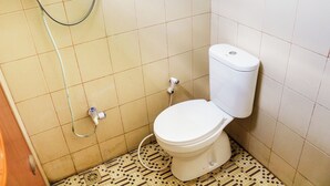 Ein kleines Badezimmer mit Toilette, Duschschlauch und Fliesenboden.