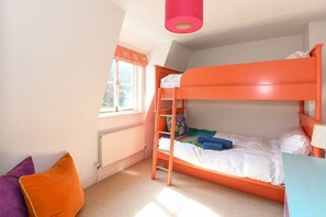 Une chambre avec un lit superposé, une fenêtre, un radiateur et un bureau.