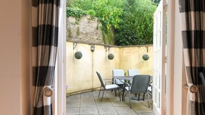 Een terras buiten met een tafel, stoelen, een stenen muur en hangende bolvormige decoraties.