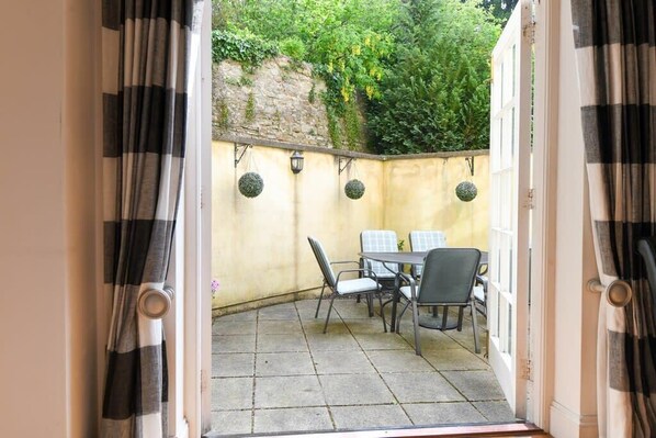 Un patio al aire libre con una mesa, sillas, un muro de piedra y decoraciones esféricas colgantes.