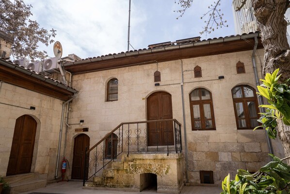 A building with stone walls, wooden doors, and a staircase with wrought iron railings.