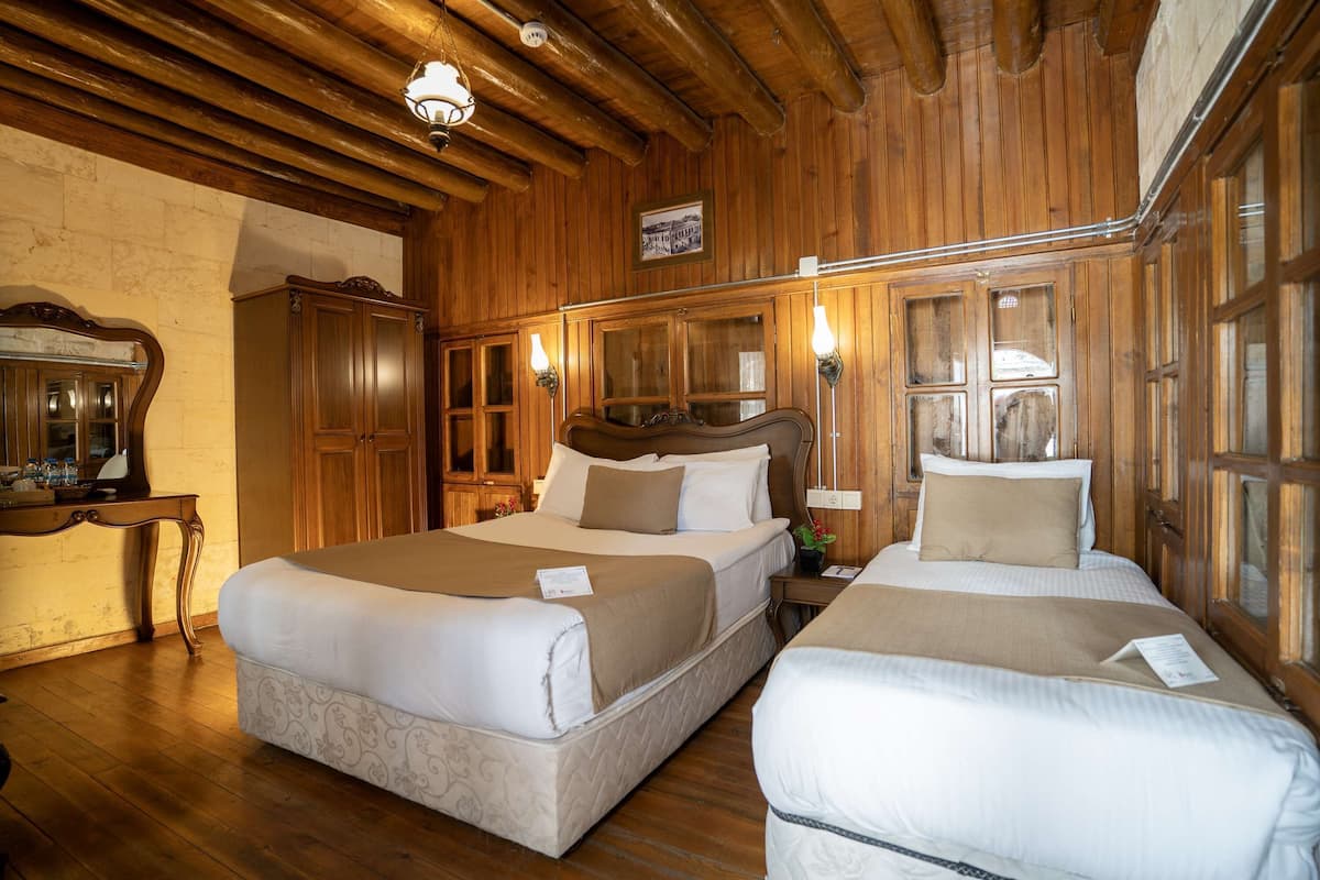 Una habitación con dos camas, paredes y techo de madera, y un espejo.