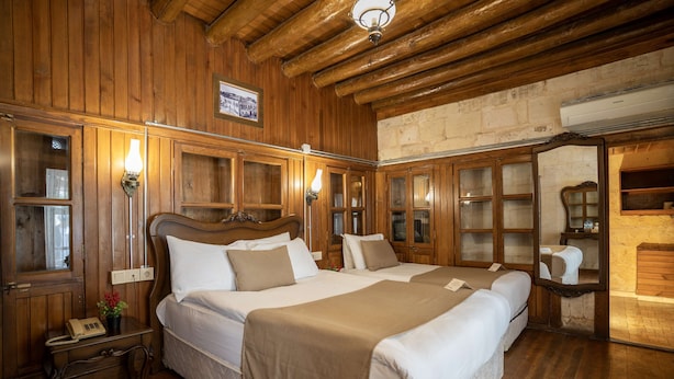 A wooden-paneled room with two beds, a telephone, and a mirror. - Aysel Hanım Konağı (Gaziantep)