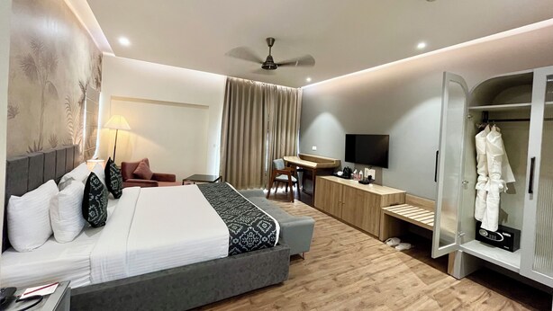 A modern hotel room with a bed, desk, wardrobe, and a ceiling fan. - Cocasa Boutique Hotel (Varanasi)