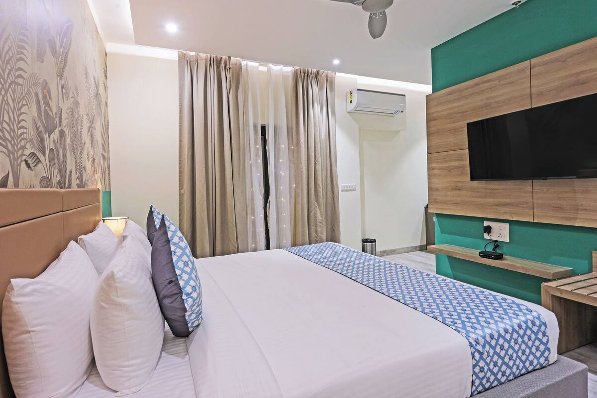 Una habitación de hotel con una cama, cortinas, un televisor y una mesita.