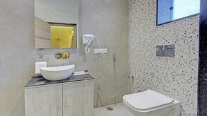 A modern bathroom with a large vessel sink, a handheld showerhead, and a toilet. - Cocasa Boutique Hotel (Varanasi)