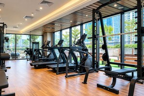 Ein modernes Fitnessstudio mit Laufbändern, Krafttrainingsgeräten und einem großen Fenster mit Blick ins Freie.