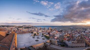 A panoramic view of a coastal city with historic architecture, a central square, and a waterfront promenade.