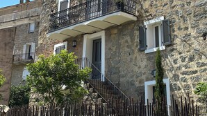 A stone building with a balcony, a wooden fence, and a clear blue sky. - Charming air-conditioned house with garden and view on the Propriano bay (Olmeto)