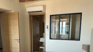 A bedroom with a bed, a bedside lamp, a wardrobe, and an air conditioning unit. - Charming air-conditioned house with garden and view on the Propriano bay (Olmeto)