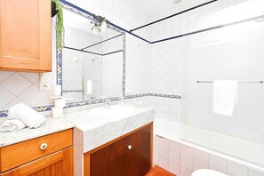 Une salle de bain avec un lavabo en marbre, des meubles en bois, un grand miroir et un espace douche.